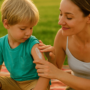 Mamma che applica una crema idratante sulla pelle del bambino dopo una giornata al sole